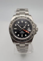 Seiko watch with black dial and silver metal strap on a light gray background