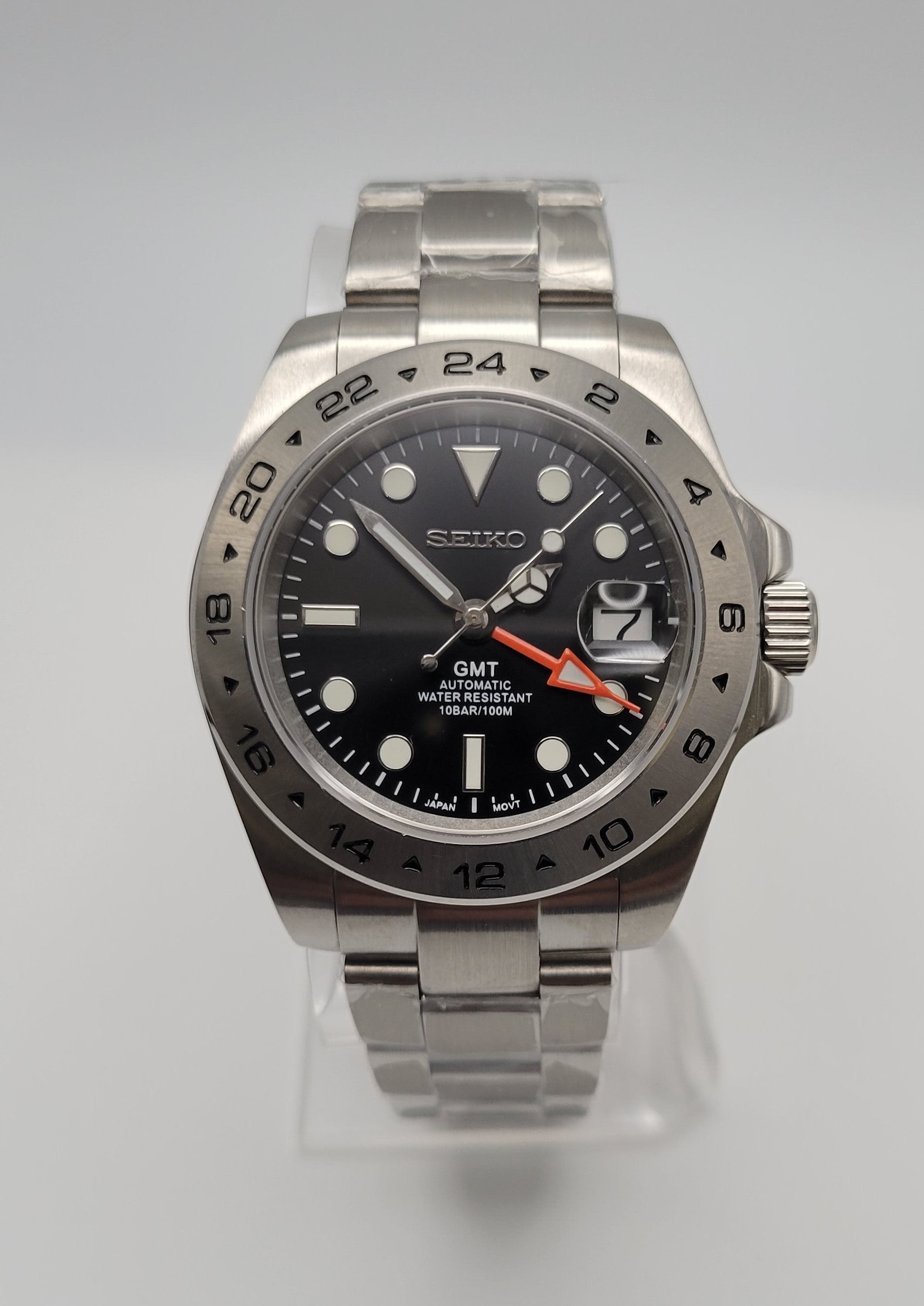 Seiko watch with black dial and silver metal strap on a light gray background