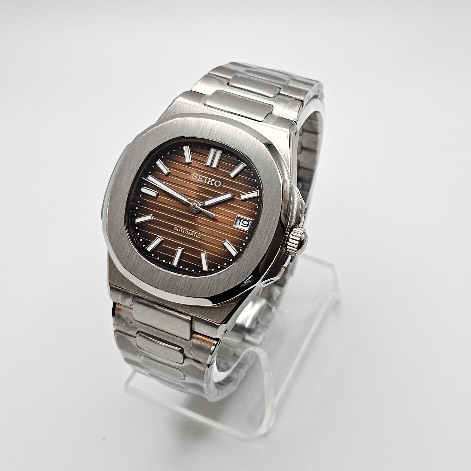 Silver Seiko watch on a clear stand against a white background