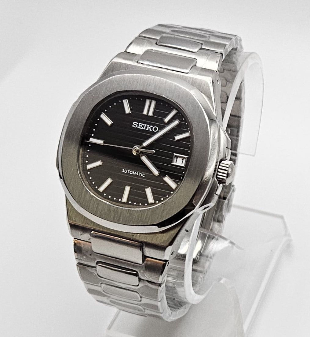Silver Seiko watch on a clear stand against a white background