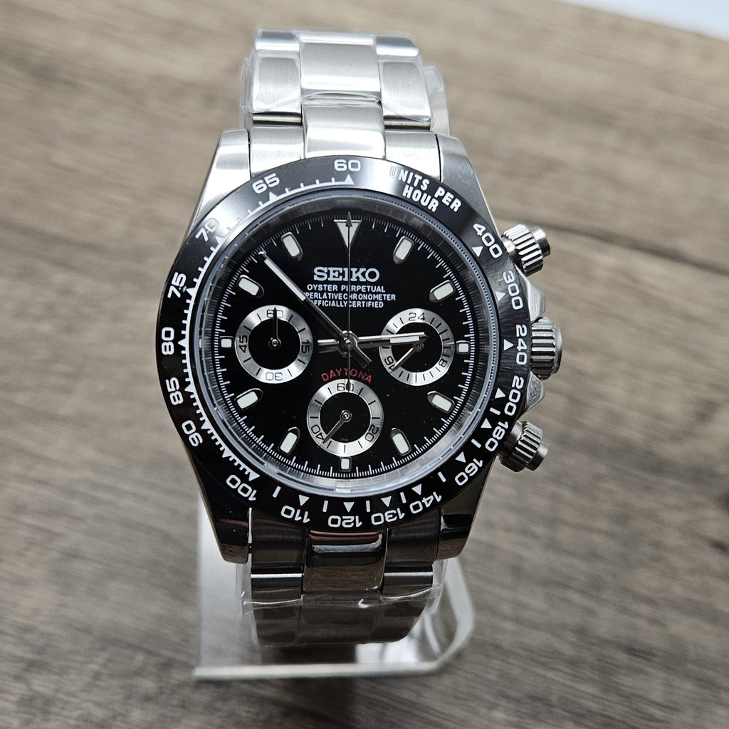 Luxury watch with black dial and silver case on a wooden surface