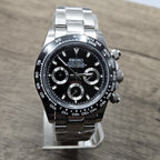 Luxury watch with black dial and silver case on a wooden surface