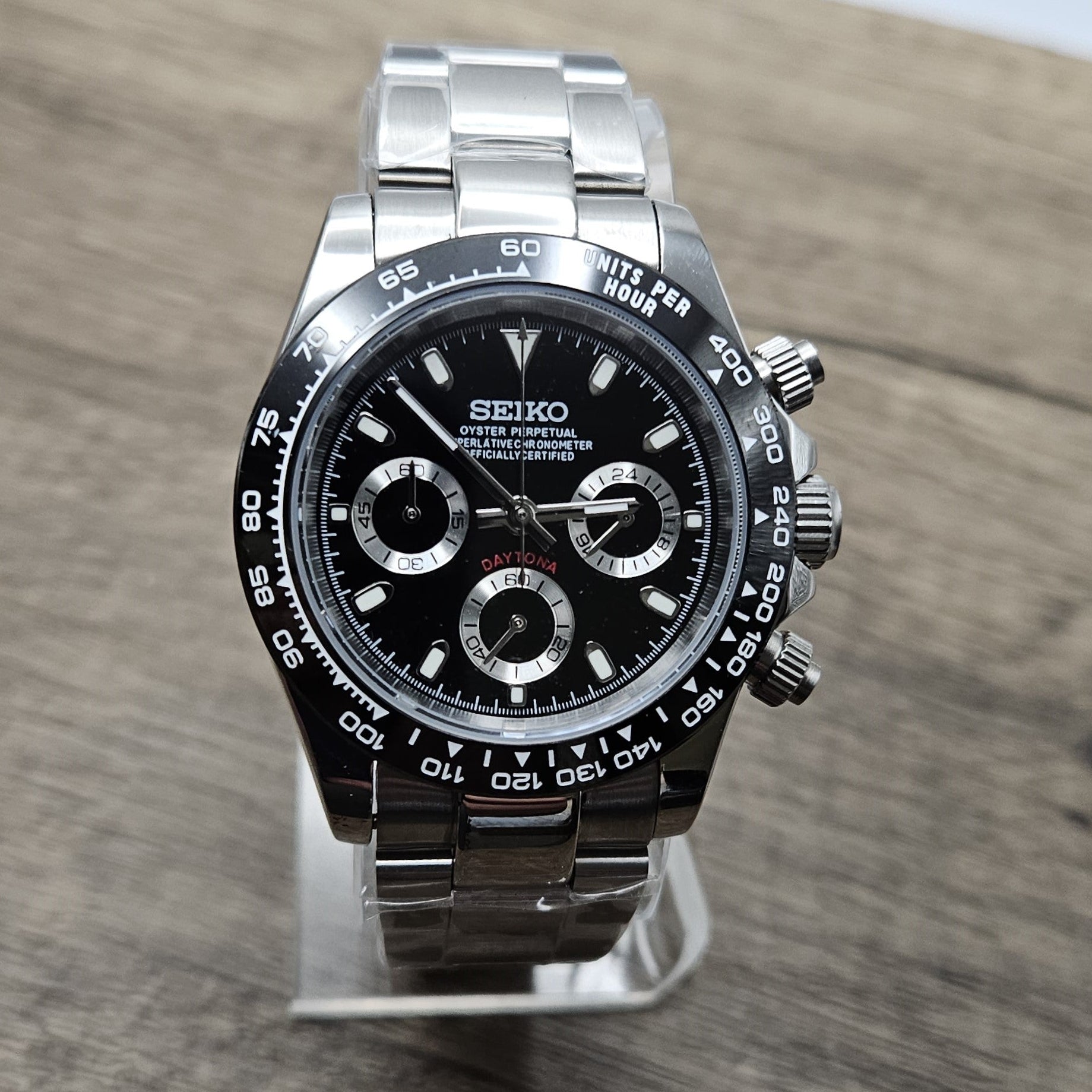 Luxury watch with black dial and silver case on a wooden surface