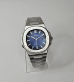A custom Seiko Nautilus watch with a blue dial, stainless steel integrated bracelet, and a transparent case back displayed on a stand.