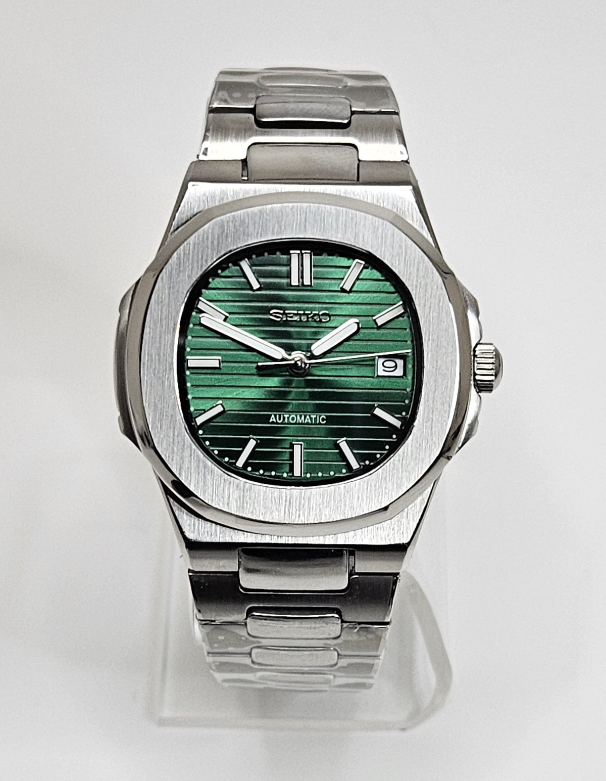 Silver Seiko watch with green face on a white background