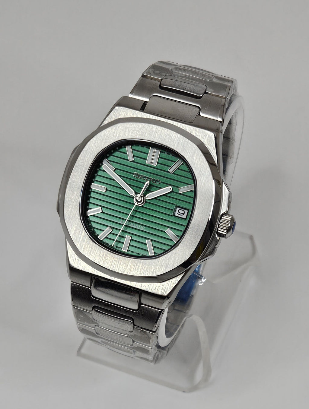 Silver watch with a green face on a gray background