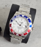 Silver watch with a red and blue bezel on a gray surface