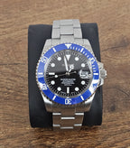 Wristwatch with blue bezel and silver band on wooden surface