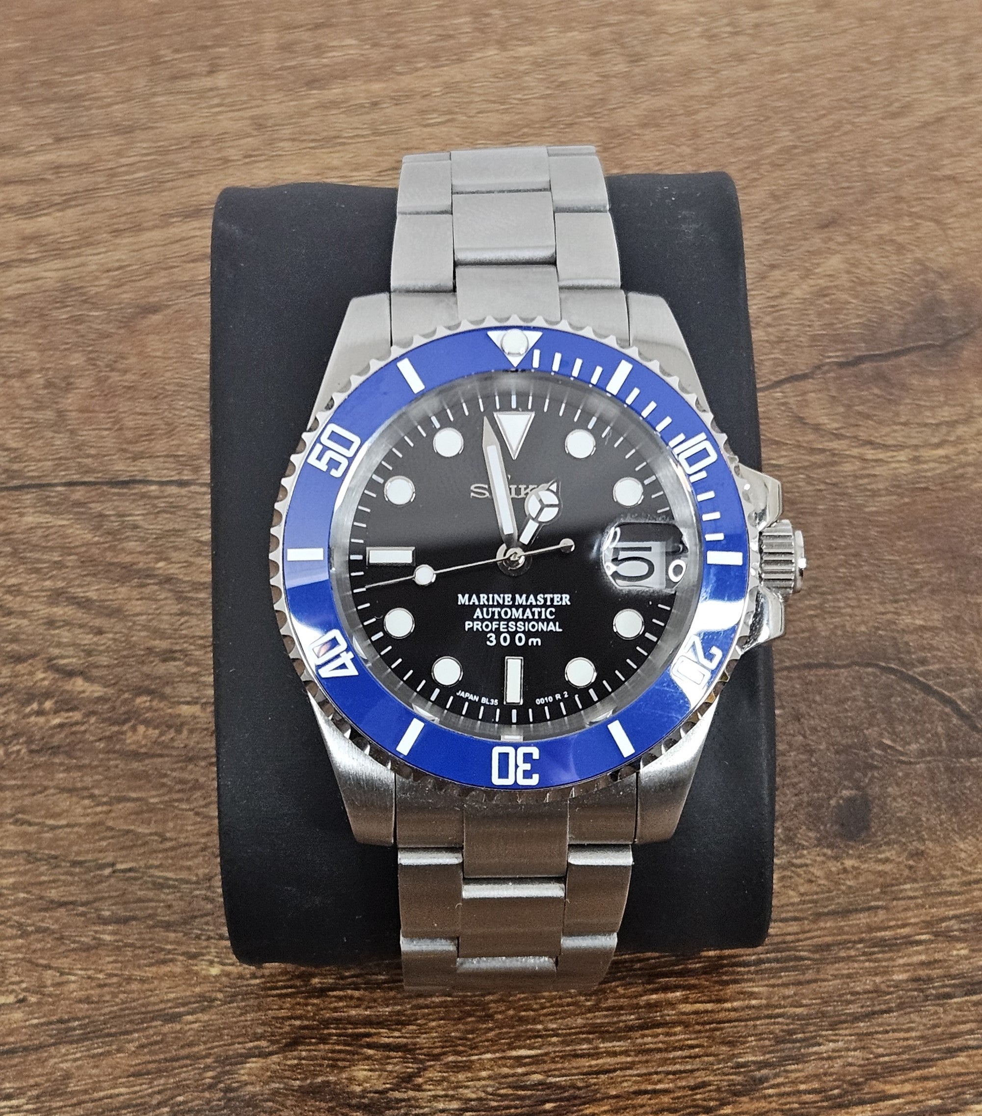 Wristwatch with blue bezel and silver band on wooden surface