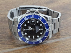Luxury watch with blue bezel and metal band on wooden surface