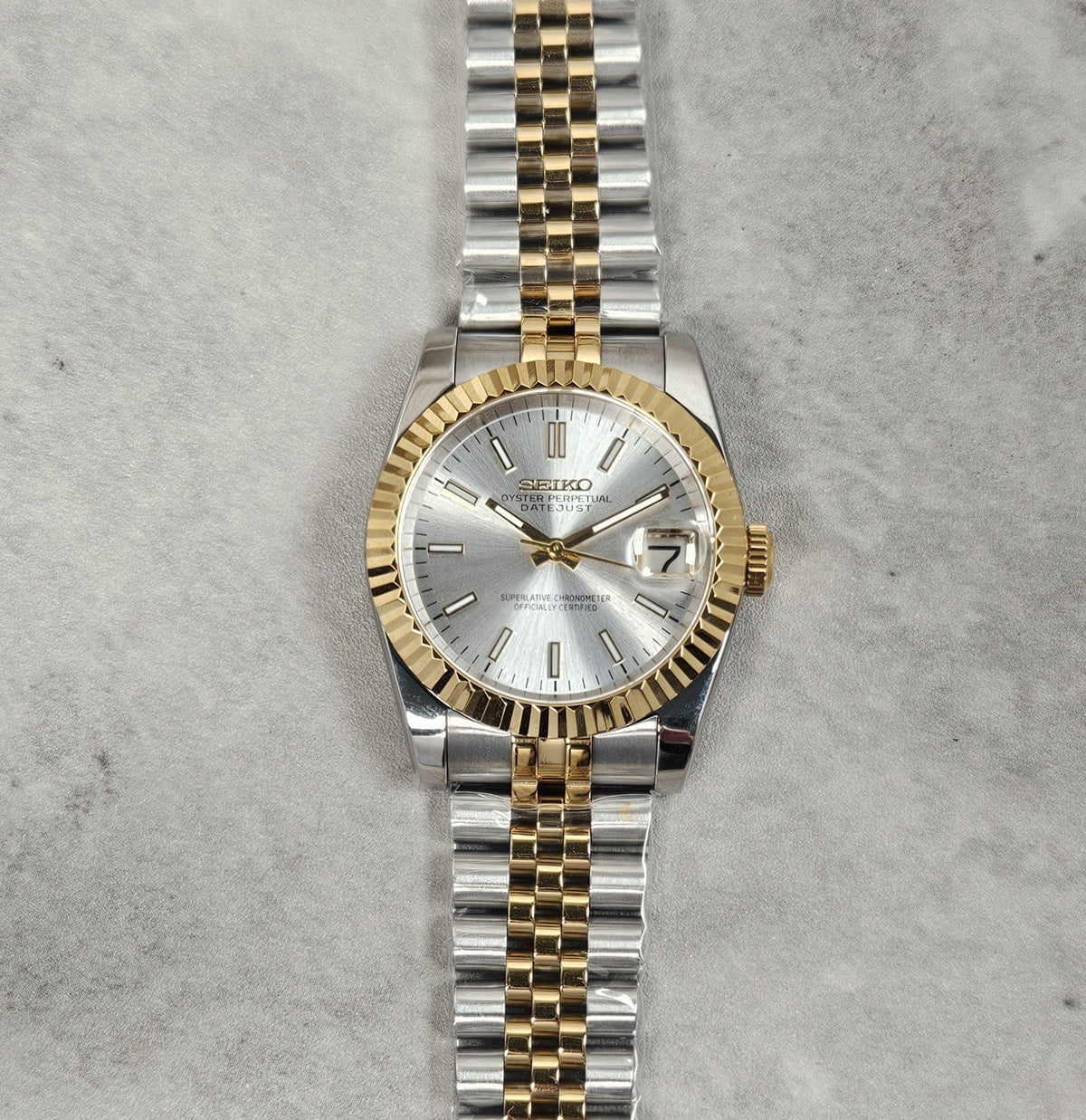 Two-tone silver and gold watch on a textured gray background