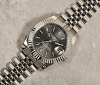 Silver watch with a dark face on a textured surface
