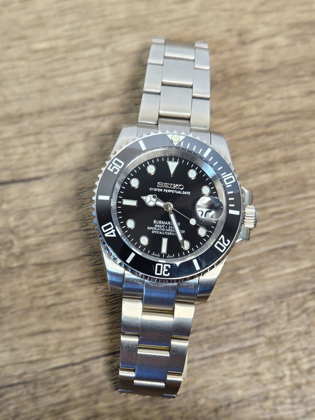 Silver watch with a black face on a wooden surface