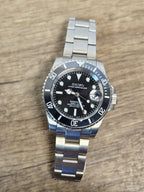 Silver watch with a black face on a wooden surface