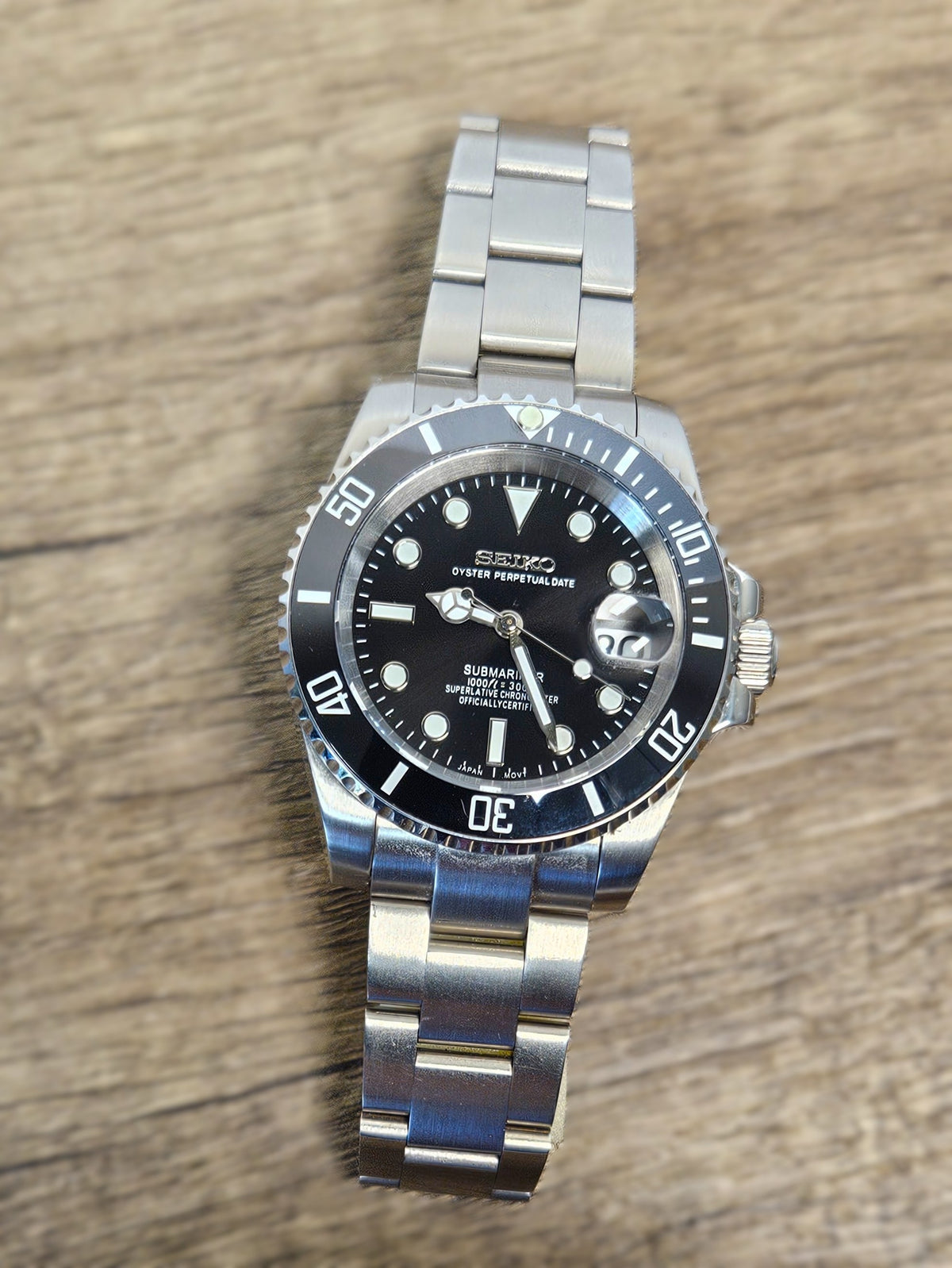 Silver watch with a black face on a wooden surface