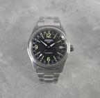 Seiko watch with black dial and silver metal strap on a gray background