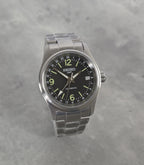 Seiko watch with black dial and silver metal strap on a gray background