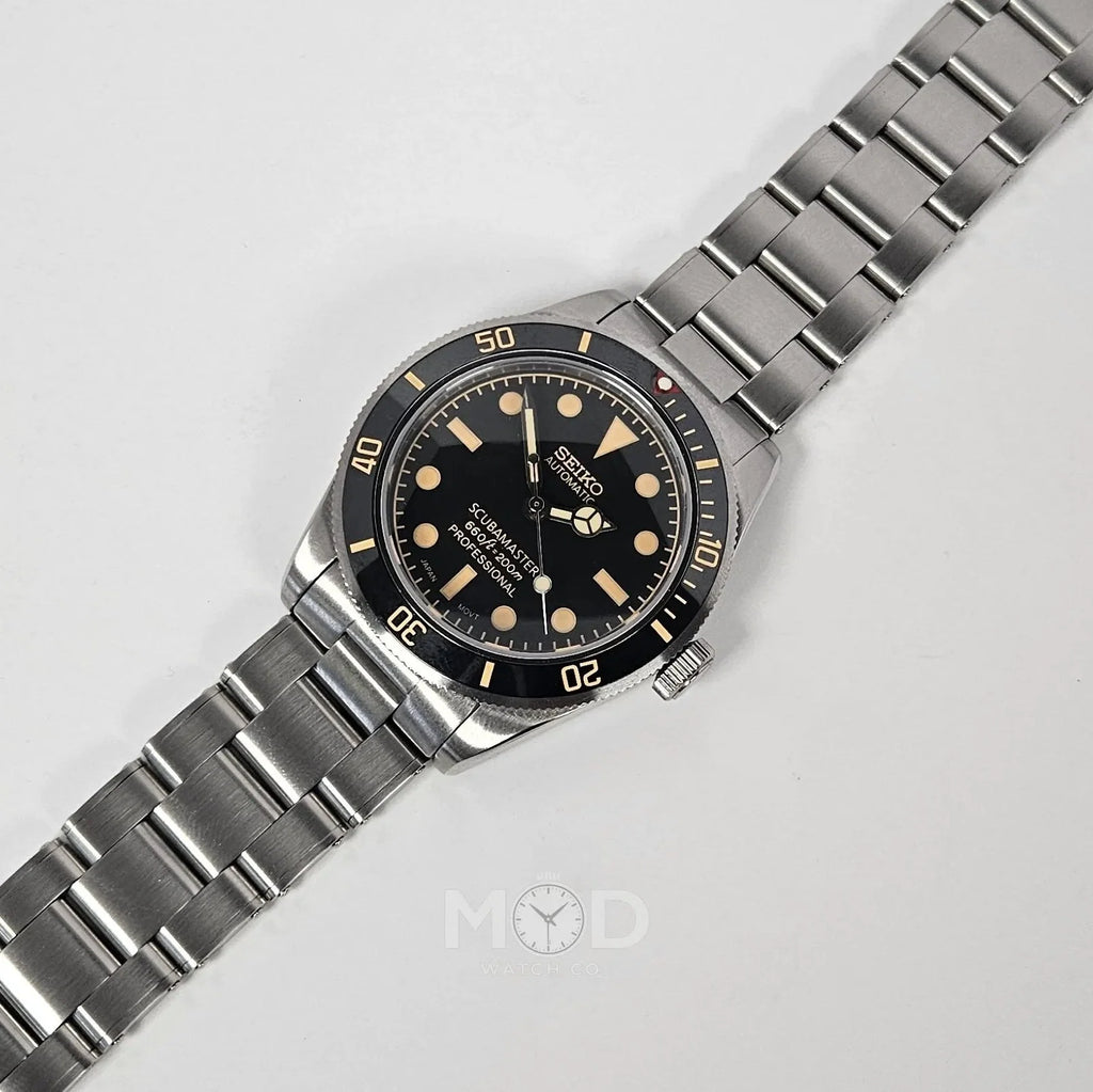 Silver wristwatch with black dial on a light gray background