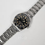 Silver wristwatch with black dial on a light gray background
