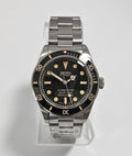 Seiko watch with black dial and silver metal strap on a light gray background