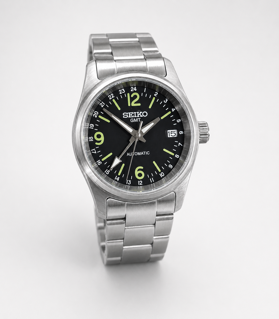 Seiko watch with black dial and silver metal strap on a white background