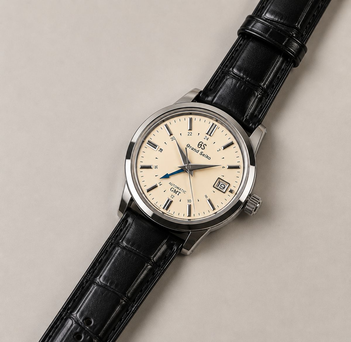 Wristwatch with black leather strap and cream dial on a beige background
