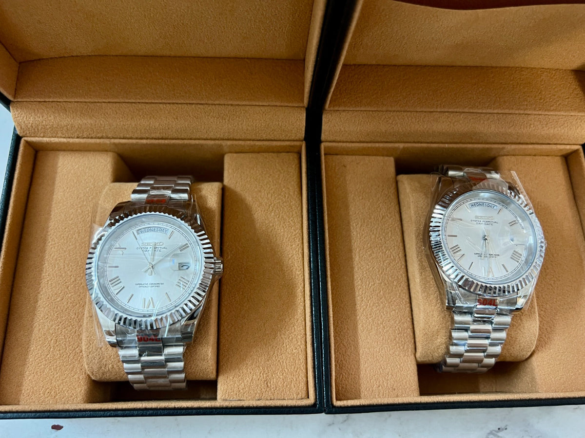 Two silver watches in a beige display case