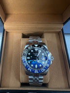 Luxury watch with blue bezel and silver case in a brown box