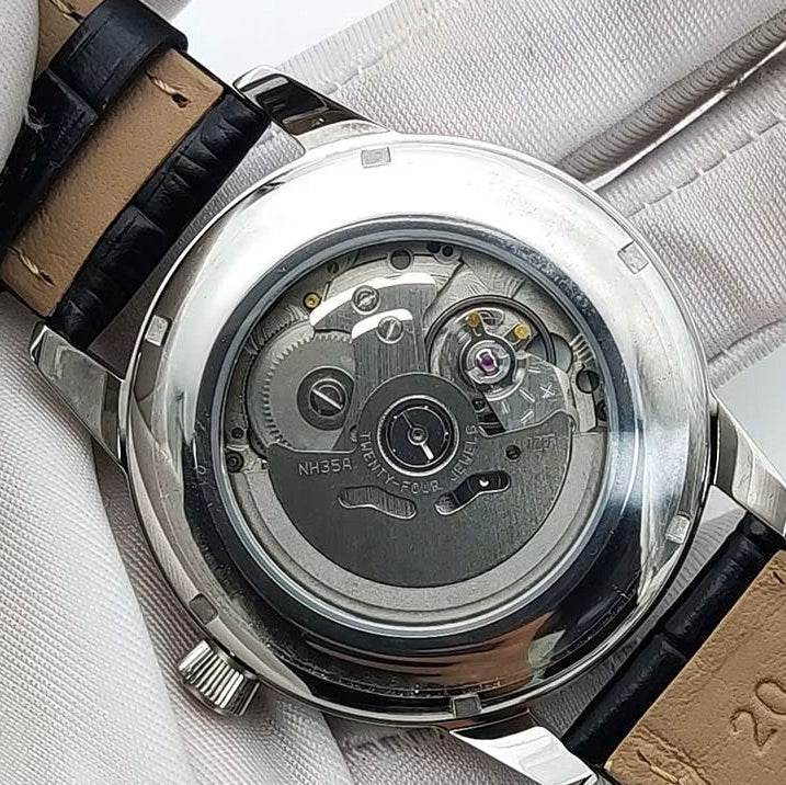 Watch with a brown leather strap and visible mechanism, held by white gloves.