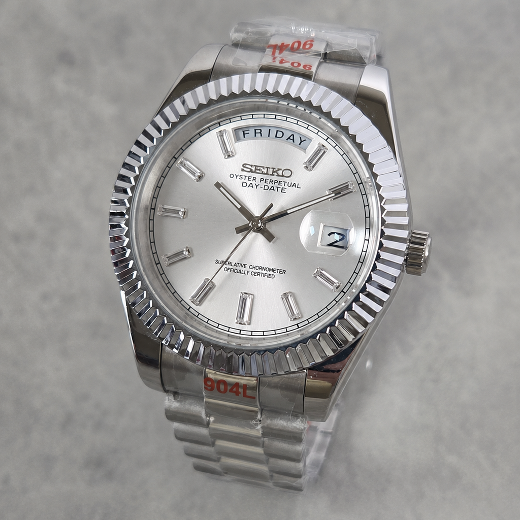 A Seiko Day-Specific wristwatch with a silver-tone stainless steel fluted bezel, silver dial, and matching steel link bracelet, shown on a light gray textured background.